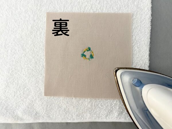 刺繍した布にタオルを当ててアイロンをかけるところ。